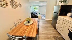 Une cuisine moderne avec une table à manger en bois, des meubles blancs et un réfrigérateur encastré.