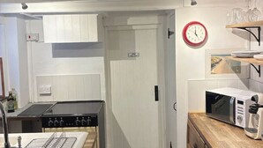 Une petite cuisine équipée d’une cuisinière, d’un four à micro-ondes et d’une horloge murale.