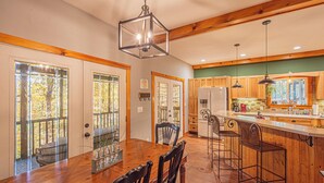 A spacious kitchen with wooden cabinets, a central island with stools, and a large dining table with chairs. - Mountain View Escape-Dog friendly, Screened Porch (Dahlonega)