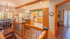 A spacious kitchen with wooden cabinets, a central island, and a dining area with chairs and a table. - Mountain View Escape-Dog friendly, Screened Porch (Dahlonega)