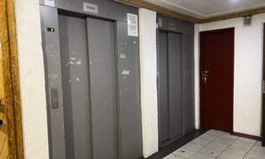 Conjunto de três elevadores cinzentos, com uma placa acima do elevador esquerdo que diz "PAIR".