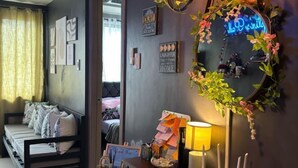 A modern bedroom with a bed, bedside table, lamp, and a decorative mirror with floral arrangements.