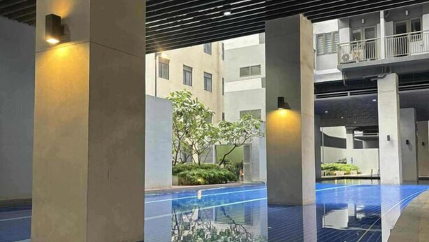 A modern indoor swimming pool with clear water, surrounded by concrete pillars and a tiled floor.