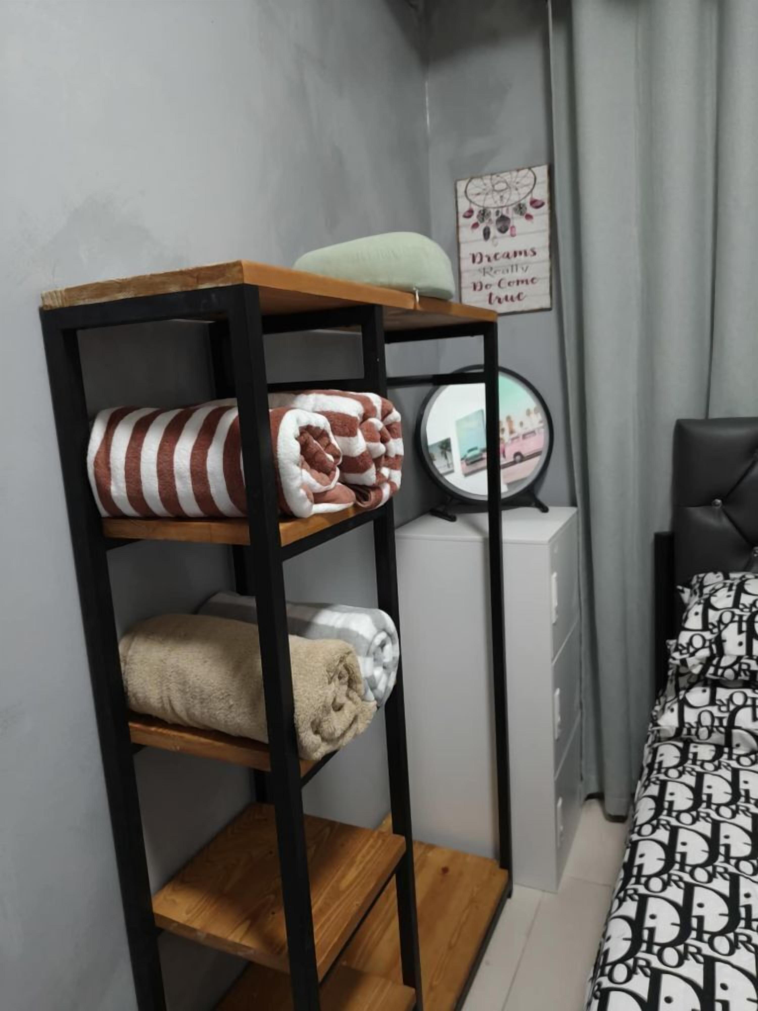 A bunk bed with striped and plain blankets, a small wooden shelf, and a wall clock.