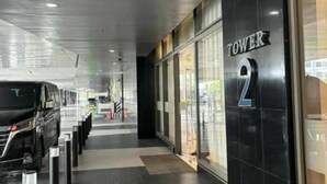 A modern building entrance with a black facade and a sign reading "TOWER 2".