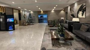 A spacious lobby with a modern design, featuring a reception desk, seating area, and a Christmas tree.
