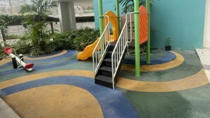 A playground with a slide, seesaw, and a covered play area. - Modern Studio Retreat at Mesavirre Residences (Bacolod City)