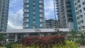 Un immeuble résidentiel de grande hauteur, doté de nombreux balcons et entouré d’autres immeubles de grande hauteur.
