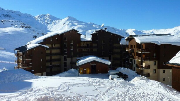 A multi-story hotel with a snow-covered roof, surrounded by mountains. - 2 Rooms FOR 4 People With Bedroom With South West Facing Balcony (Les Belleville)