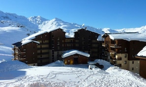 A multi-story hotel with a snow-covered roof, surrounded by mountains. - 2 Rooms FOR 4 People With Bedroom With South West Facing Balcony (Les Belleville)