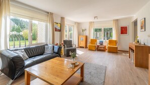 A spacious living room with a leather sofa, wooden coffee table, and yellow armchairs. - Charming Villa Near the sea and Forest (De Koog)