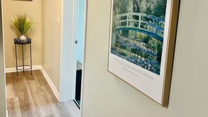Ein Flur mit einem gerahmten Monet-Gemälde, einem Blumentopf und einer Tür zu einem anderen Raum.