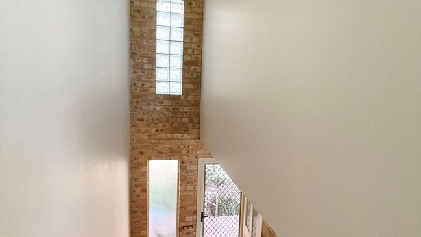 A narrow hallway with exposed brick walls and a high ceiling. - Ocean Shores Apartment 3 (South West Rocks)