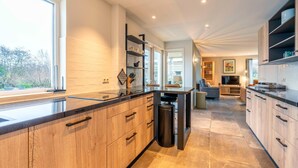 A modern kitchen with wooden cabinets, a black countertop, and a large window.