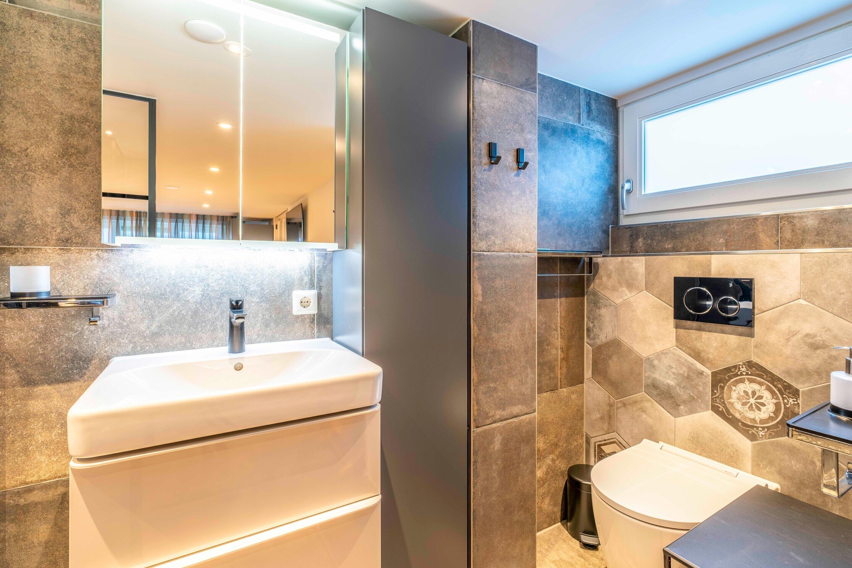 Un bagno moderno con un ampio specchio, un lavandino bianco, un water e una cabina doccia.