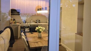 Een moderne keuken met een eethoek, met een groot raam, een inbouwoven en een eettafel met stoelen.