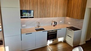 Een moderne keuken met witte kasten, een inbouwoven en een RVS-spoelbak.