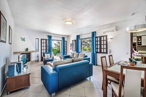 Een moderne woonkamer met een blauwe bank, een eettafel en een open haard.