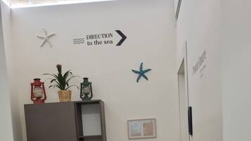 A hallway with a directional sign to the sea, a fire extinguisher, a wooden cabinet, and a small table.