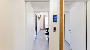Un pasillo con una puerta a la derecha, un cierre electrónico y una ventana con cortinas.
