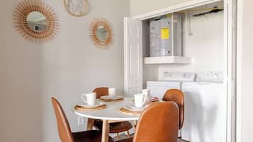 A dining area with a round table, four chairs, and a round rug.