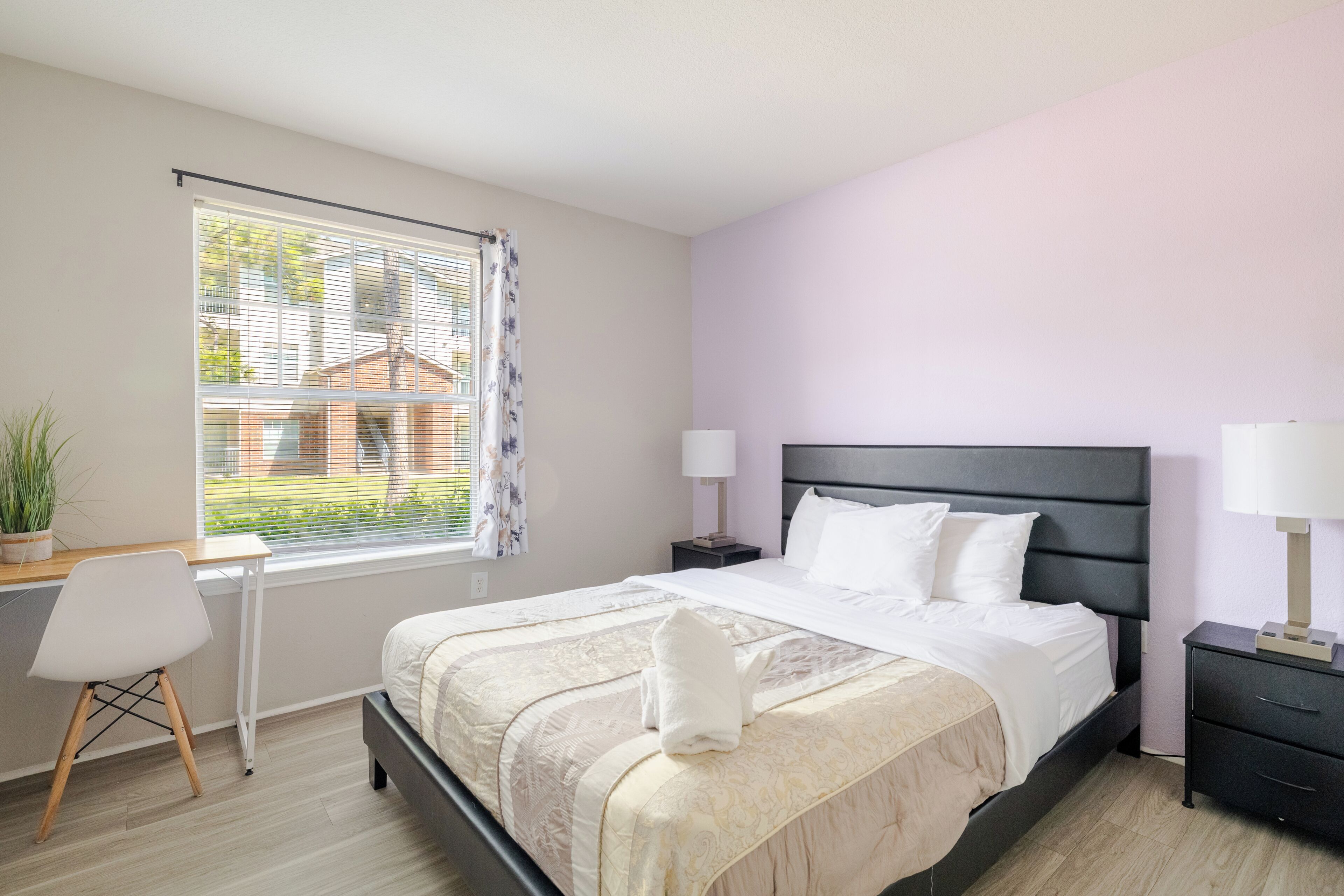 A bedroom with a bed, bedside tables, a desk, and a chair.