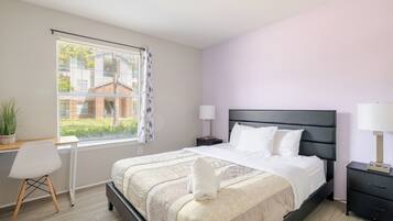A bedroom with a bed, bedside tables, a desk, and a chair.