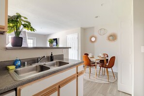 Une cuisine moderne dotée d’un plan de travail en granit, d’un évier en acier inoxydable et d’un coin repas avec une table ronde et des chaises.
