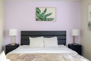 Une chambre à coucher avec un lit, deux tables de chevet et un tableau accroché au mur.