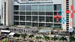 Een modern stadion met een grote glazen gevel en een opvallend bord met de tekst 'nrg stadium'.