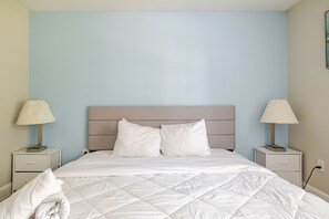 A neatly made bed with white linens, two bedside tables with lamps, and a light blue wall. - Central 3bed 2bath, 5 min Walk to NRG, near MDC (Houston)