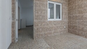 Una habitación con paredes de piedra, una ventana y una puerta que da a otra estancia.
