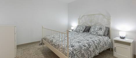 Un dormitorio con cama, mesita de noche, armario y ventilador de techo.