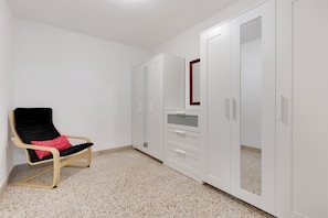 A room with a chair, wardrobe, and a mirror.