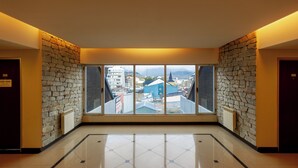 A hotel lobby with a stone wall, large windows, and a tiled floor. - Alojar Towers (Ushuaia)