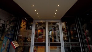 A building entrance with a glass ceiling, a red awning, and a sign indicating the entrance number. - Alojar Towers (Ushuaia)