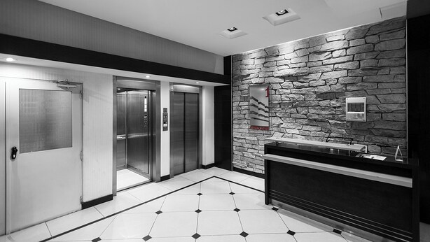 A modern elevator area with a stone wall, a reception desk, and a tiled floor. - Alojar Towers (Ushuaia)