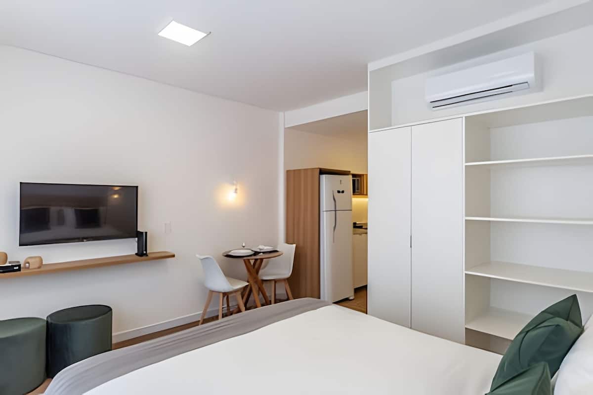 Une chambre d’hôtel moderne équipée d’un lit, d’une télévision, d’un petit coin repas et d’une kitchenette.