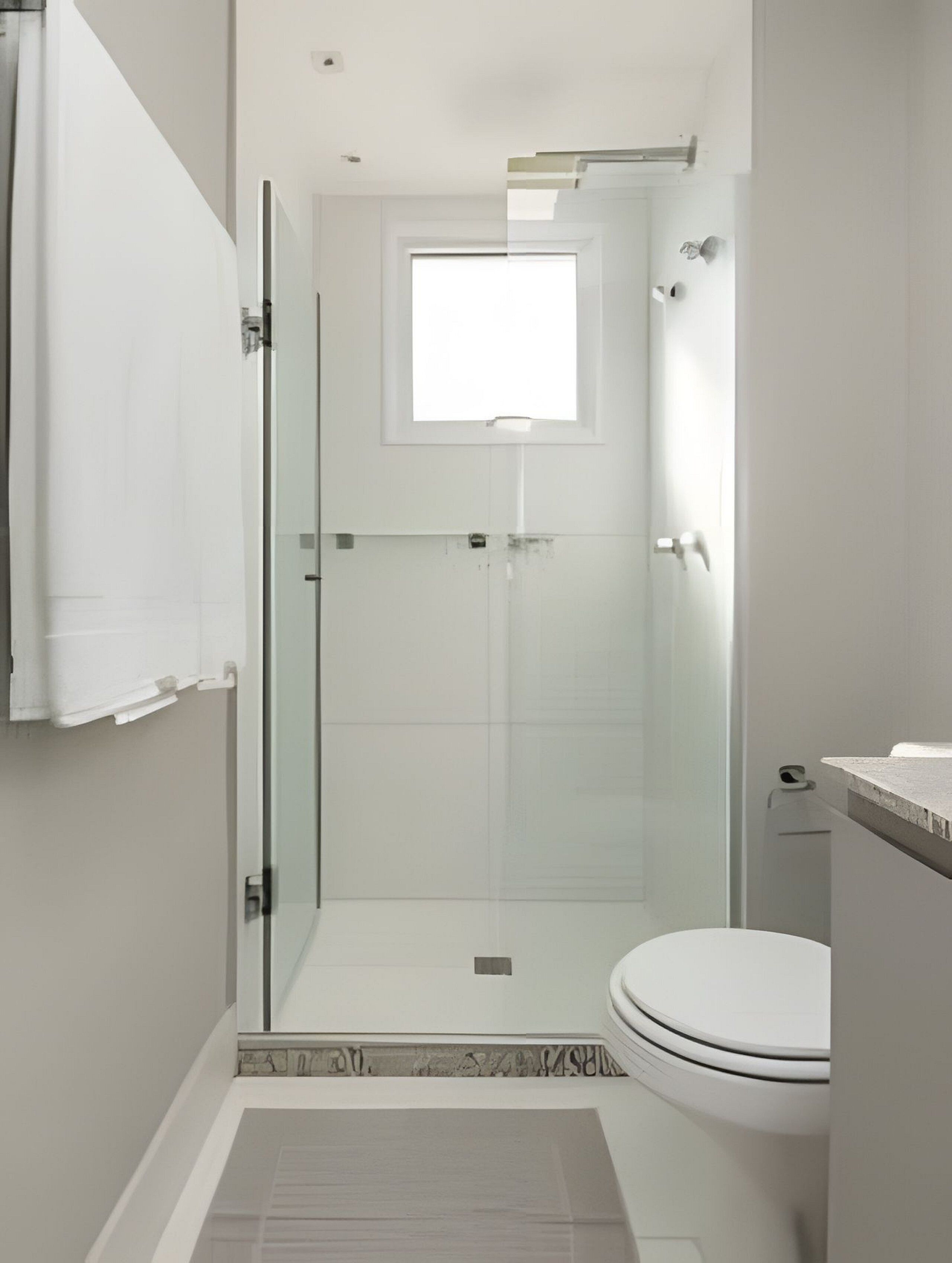 A modern bathroom with a glass-enclosed shower, a toilet, and a small window above the shower.