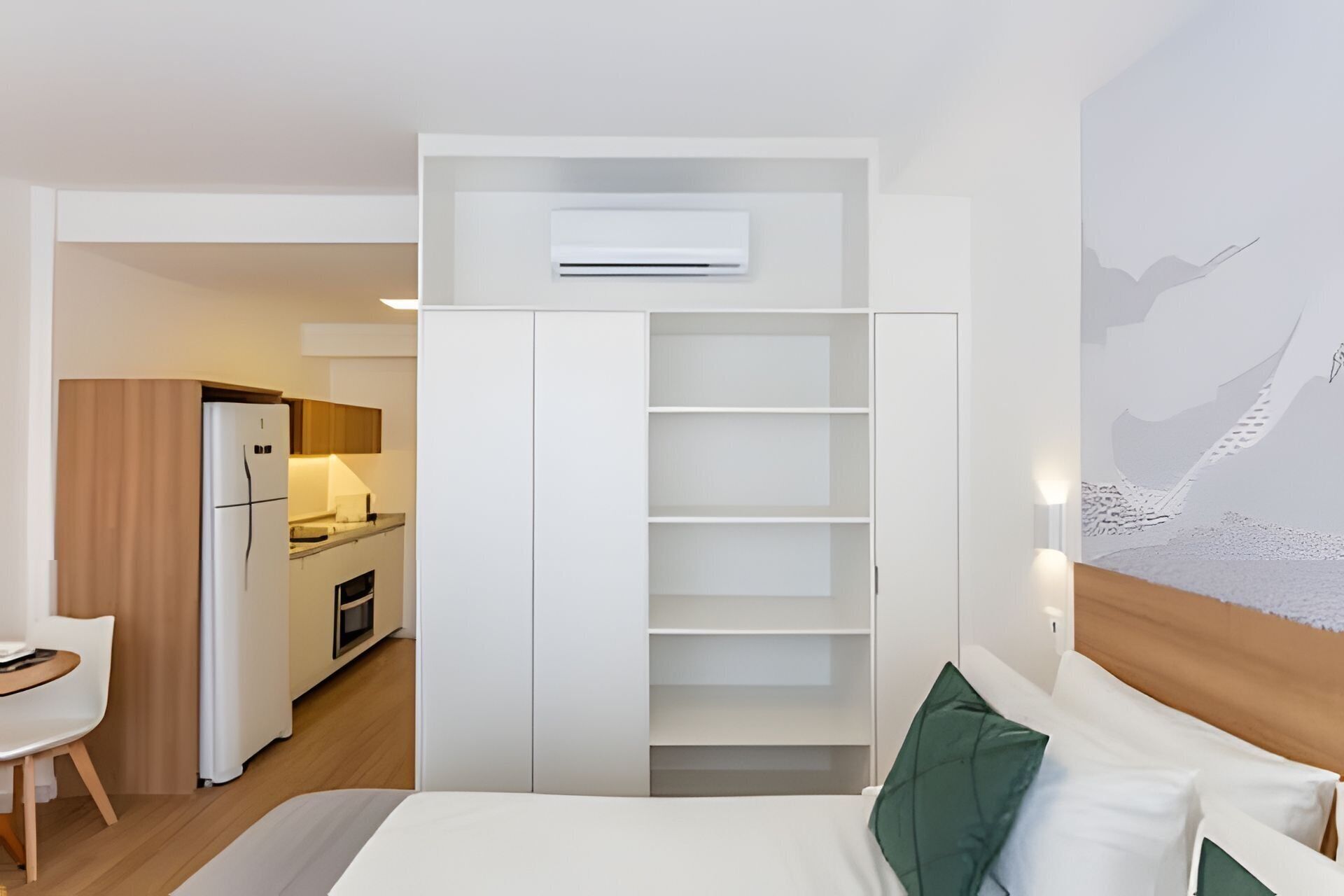 Ett kompakt hotellrum med en säng, ett litet kök och en matplats.