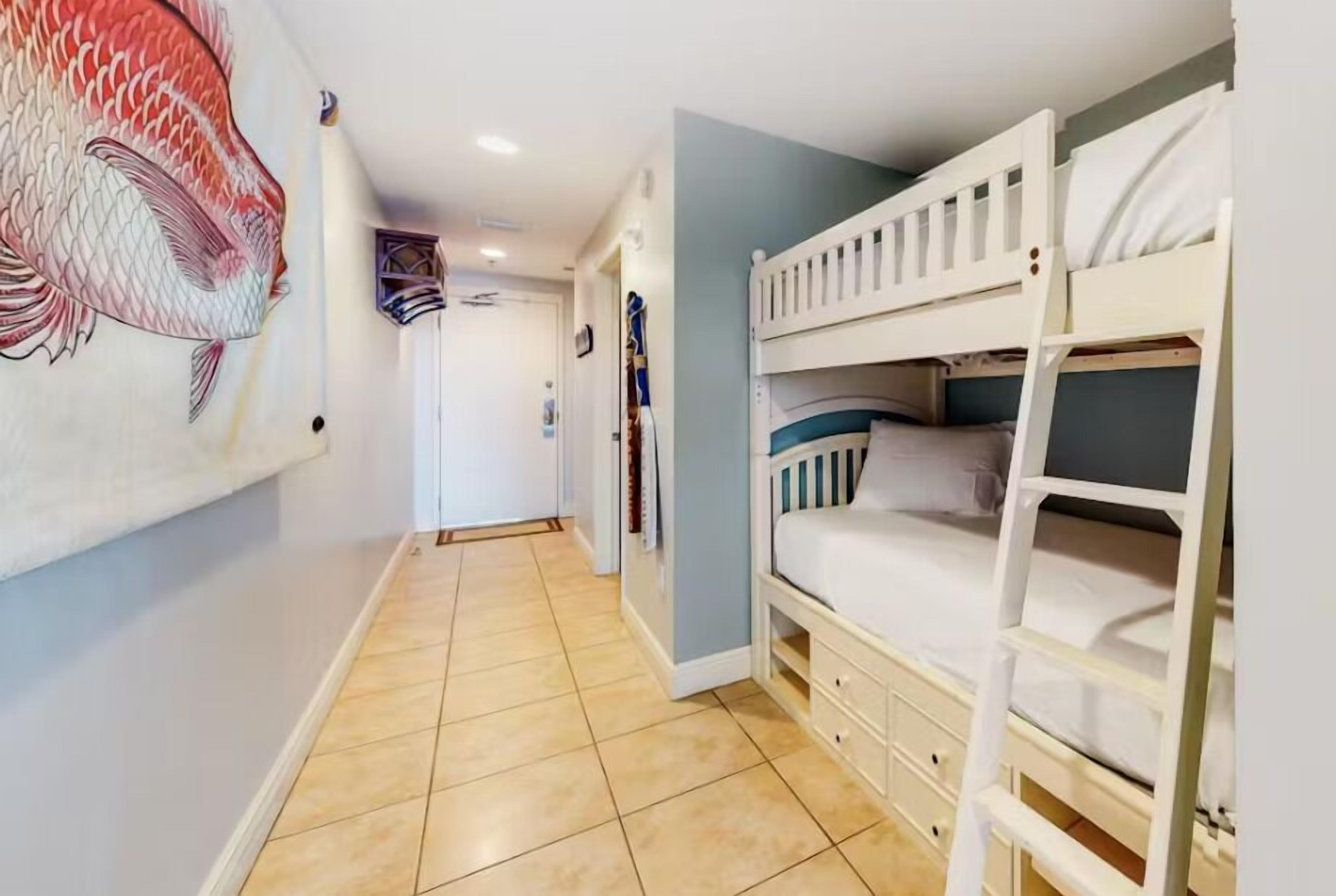 Una habitación con literas, suelo de baldosas y un gran mural de peces en la pared.