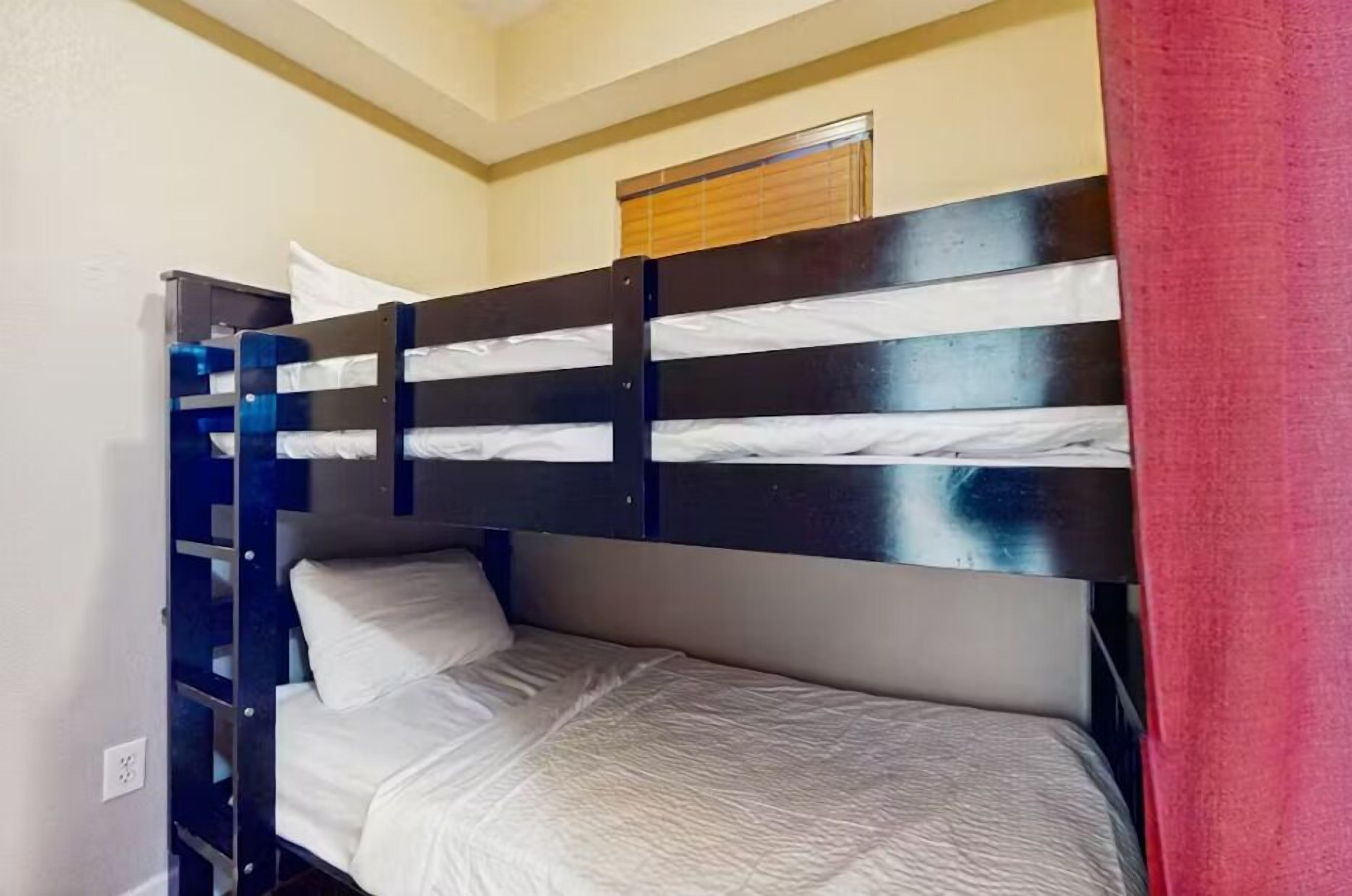 A bunk bed room with a window and a red curtain.