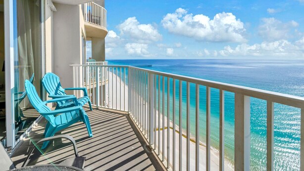 Een balkon met turquoise stoelen en uitzicht op de oceaan.