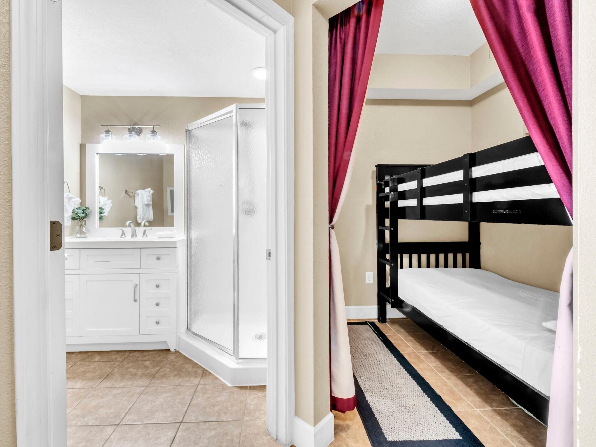 Une chambre avec un lit superposé, une salle de bain avec douche et une coiffeuse avec miroir.