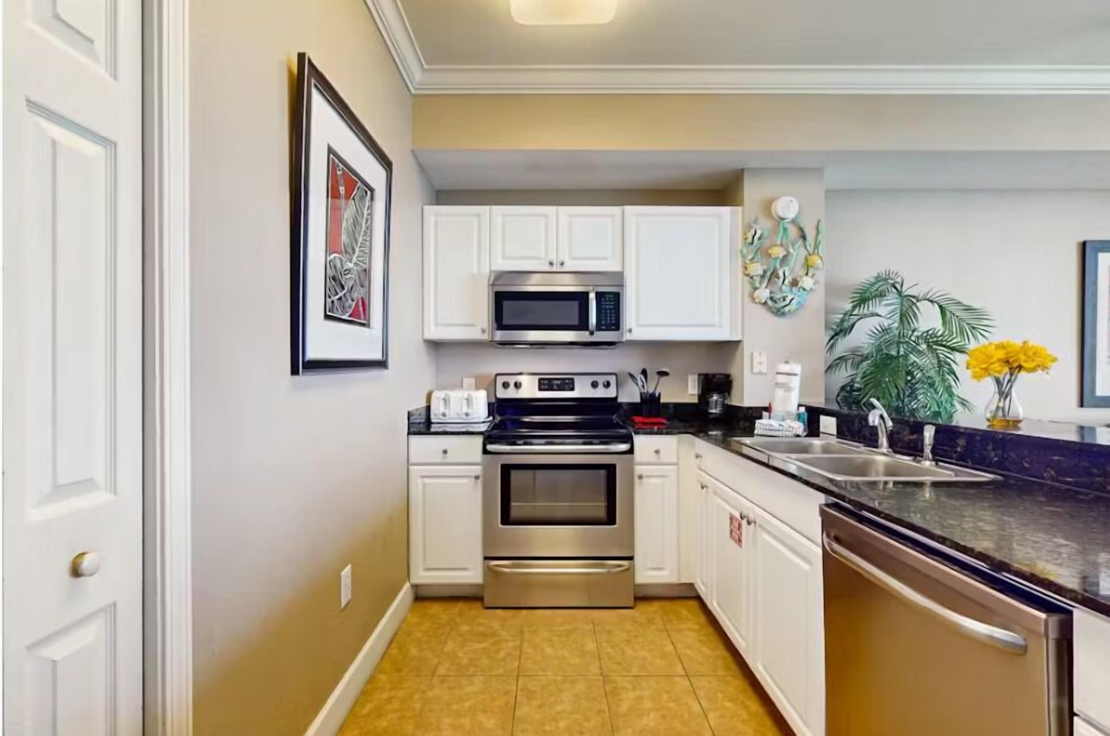 A compact kitchen with white cabinets, a stainless steel oven, a microwave, and a dishwasher.