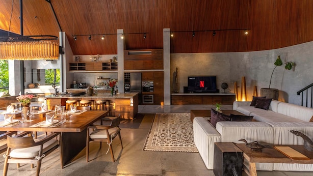 A spacious living area with a wooden ceiling, a dining table set for six, a sofa, and a TV in the background. - Boutique 6-bedroom Villa The Wing in wonderful Ubud Bali incl. Concierge Service (Ubud)