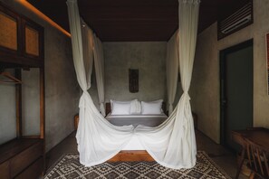A four-poster bed with white drapes, a wooden bench, and a patterned rug in a room with a wooden ceiling and a green door. - Boutique 6-bedroom Villa The Wing in wonderful Ubud Bali incl. Concierge Service (Ubud)
