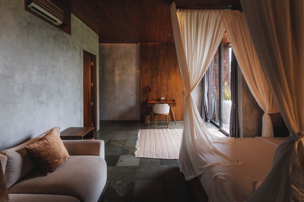 Quarto com cama, sofá, escrivaninha e cadeira.