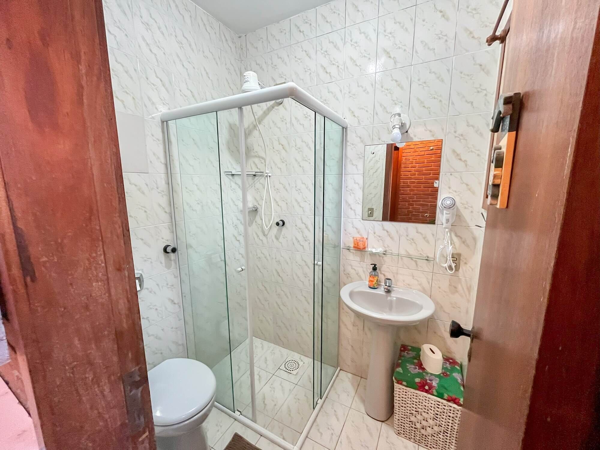 A bathroom with a glass-enclosed shower, a white sink, and a toilet.