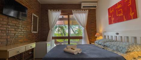 Un dormitorio con cama, televisor montado en la pared, ventilador de techo y aire acondicionado.